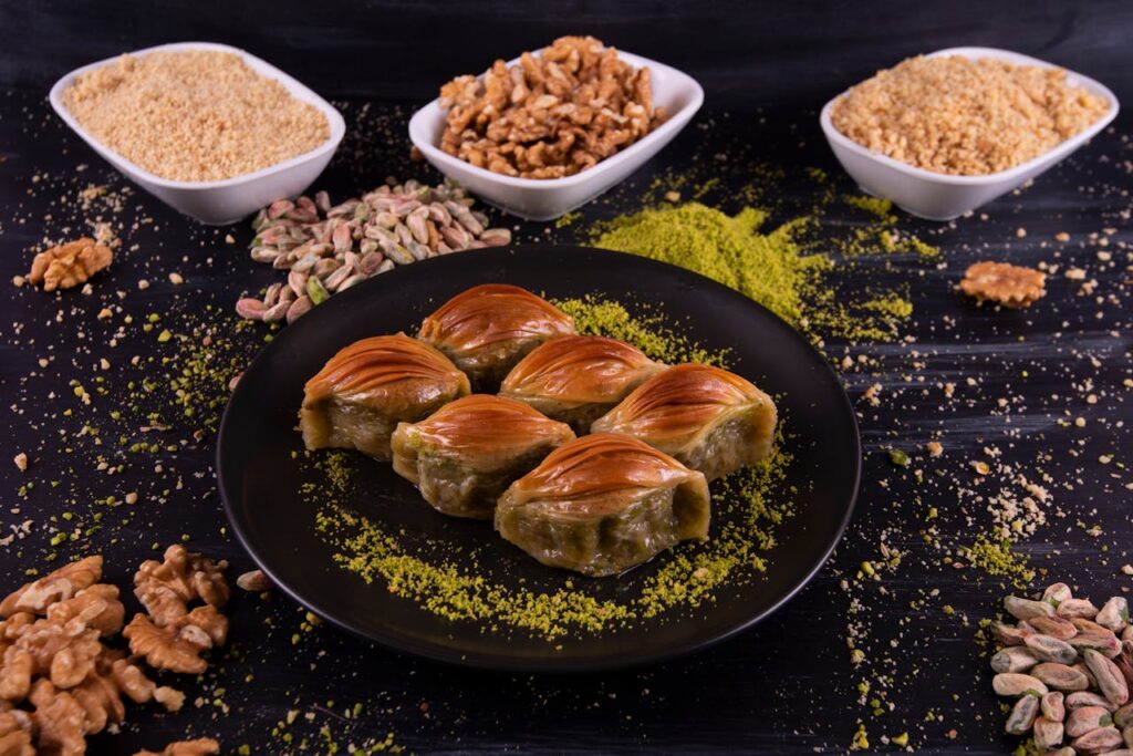 Close-up of traditional Turkish midye baklava with pistachio nuts, perfect dessert display.