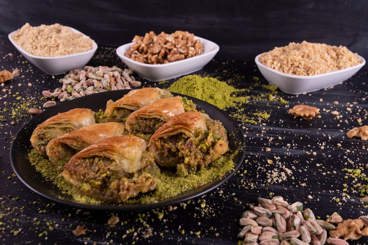 Close-up of Turkish baklava with pistachios and walnuts on a black plate.