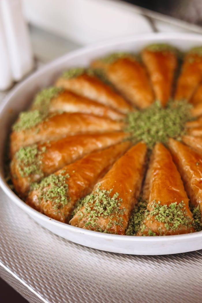 A tray of golden brown baklava sprinkled with fresh pistachios, ready to serve.