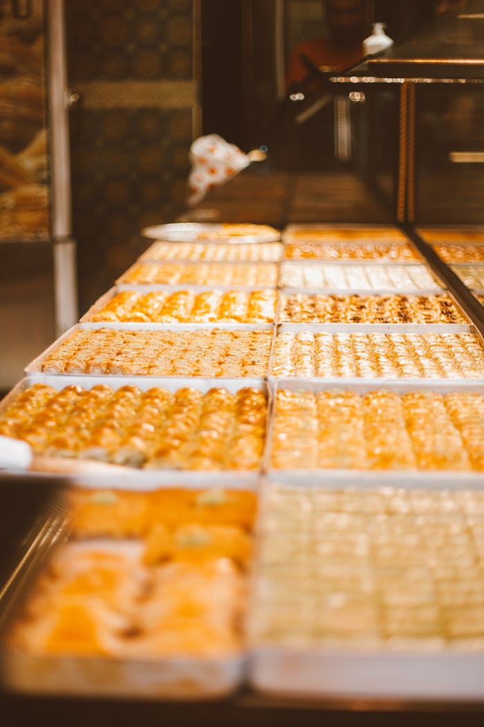 Trays of traditional sweets in a bakery shop with golden brown pastries.