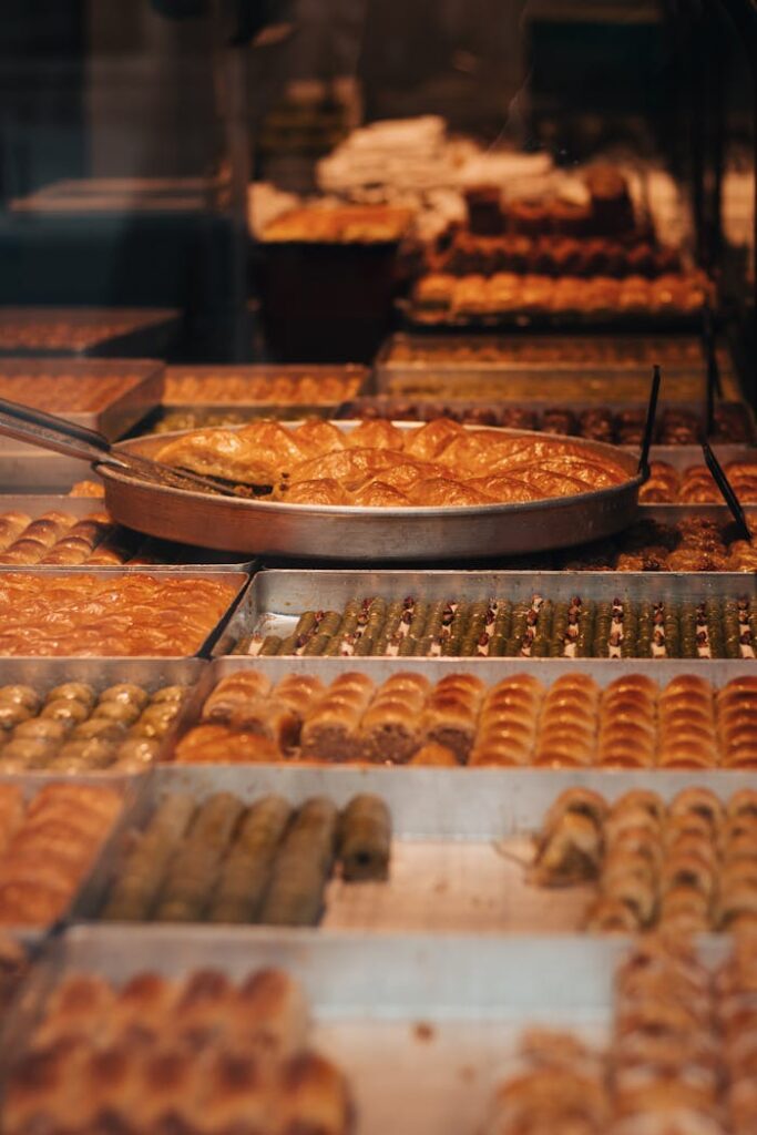 A bakery display showcasing a variety of pastries and baklava in trays, ready for sale.